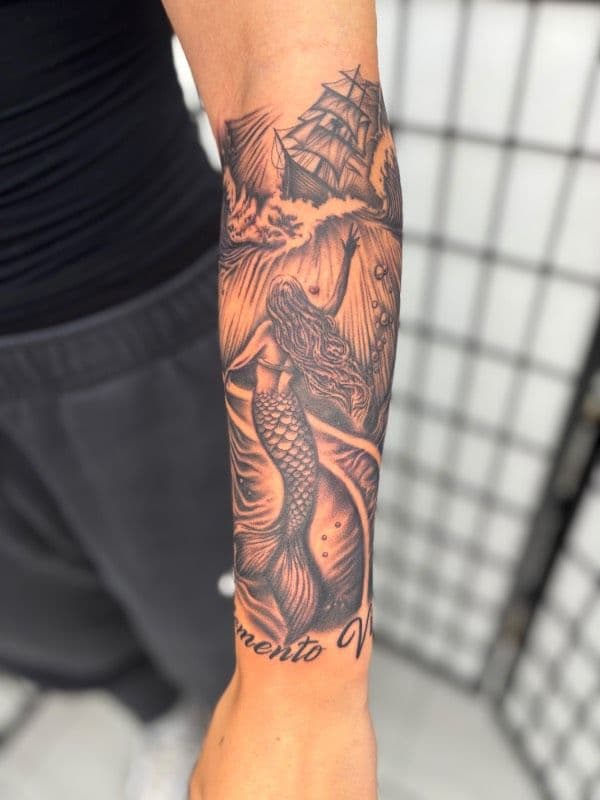 Black and grey mermaid and ship tattoo on forearm